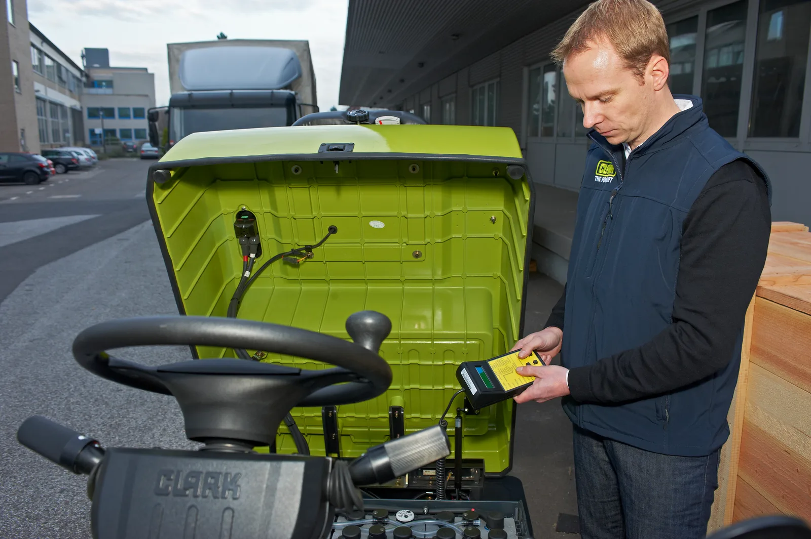 Clark-trained technician running diagnostics on a forklift with a handheld service tool
