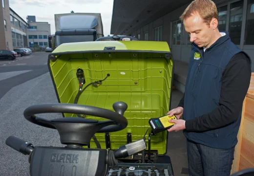 Clark-trained technician running diagnostics on a forklift with a handheld service tool